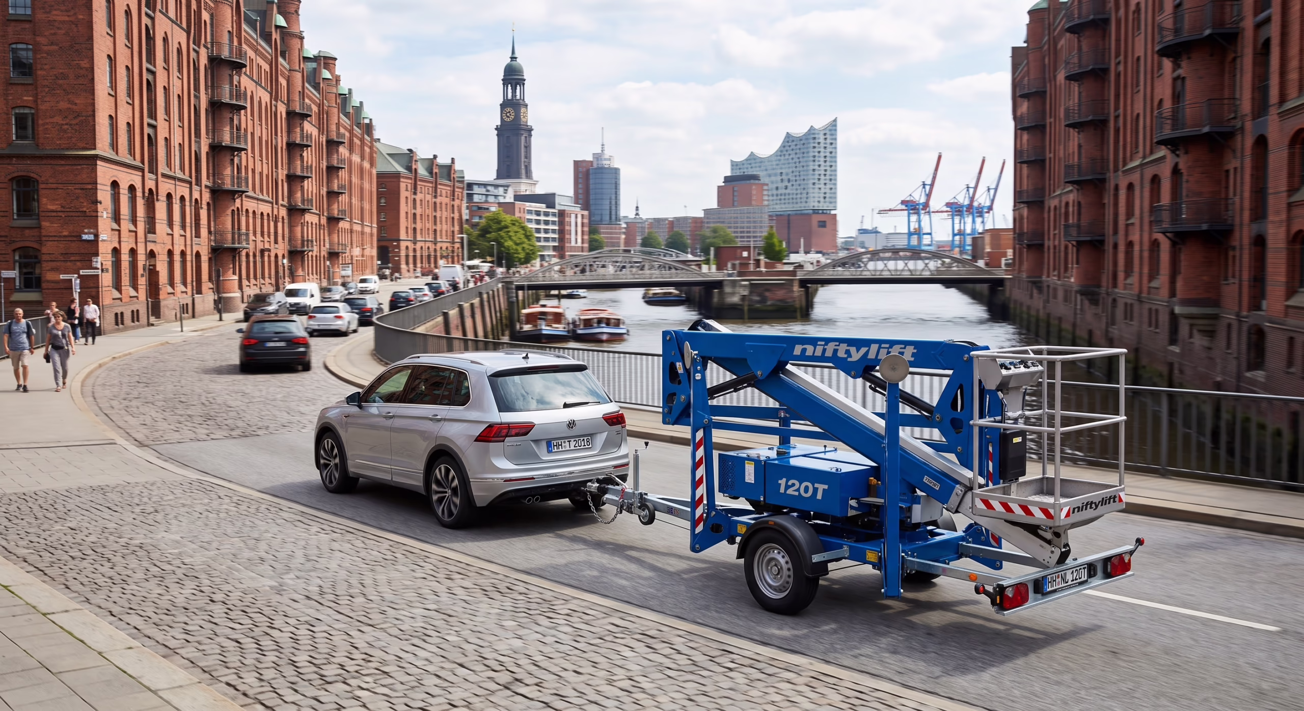 Ein VW Tiguan zieht eine blaue Niftylift 120T Anhängerarbeitsbühne auf einer Straße in Hamburg